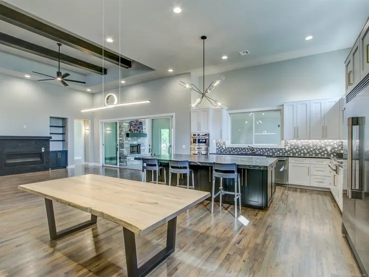 Spacious open kitchen with large island, bar stools, wooden dining table, and hardwood floors